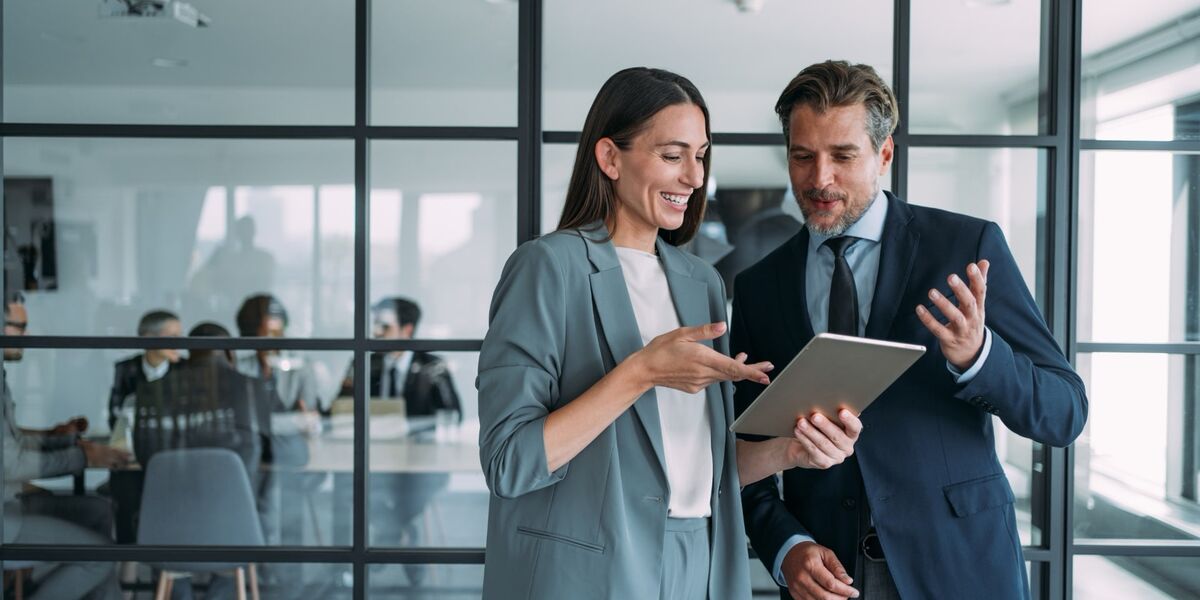 Kollegen im Büro sprechen über ein Projekt und schauen in ein Tablet. 