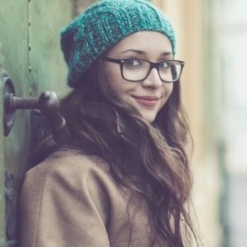Junge Frau mit Brille und Mütze.