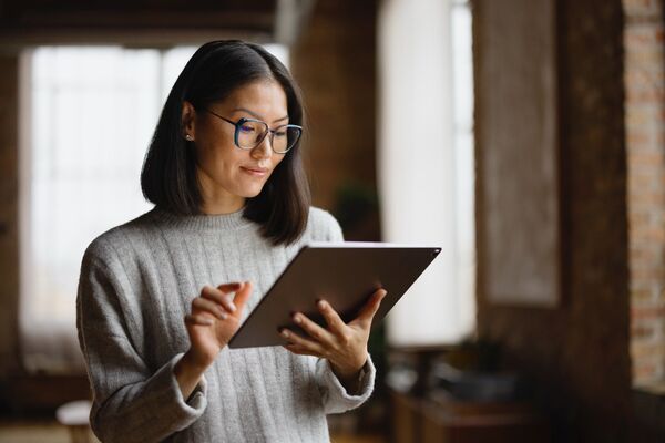 Frau mit Brille hält ein iPad in der Hand