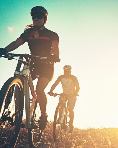 Paar mittleren Alters fährt mit Gravelbikes und Radausrüstung über eine Ebene.
