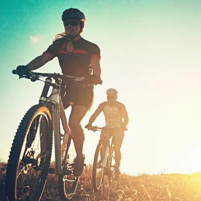 Zwei Gravel Biker in sportlicher Ausrüstung fahren auf einer Hochebene.