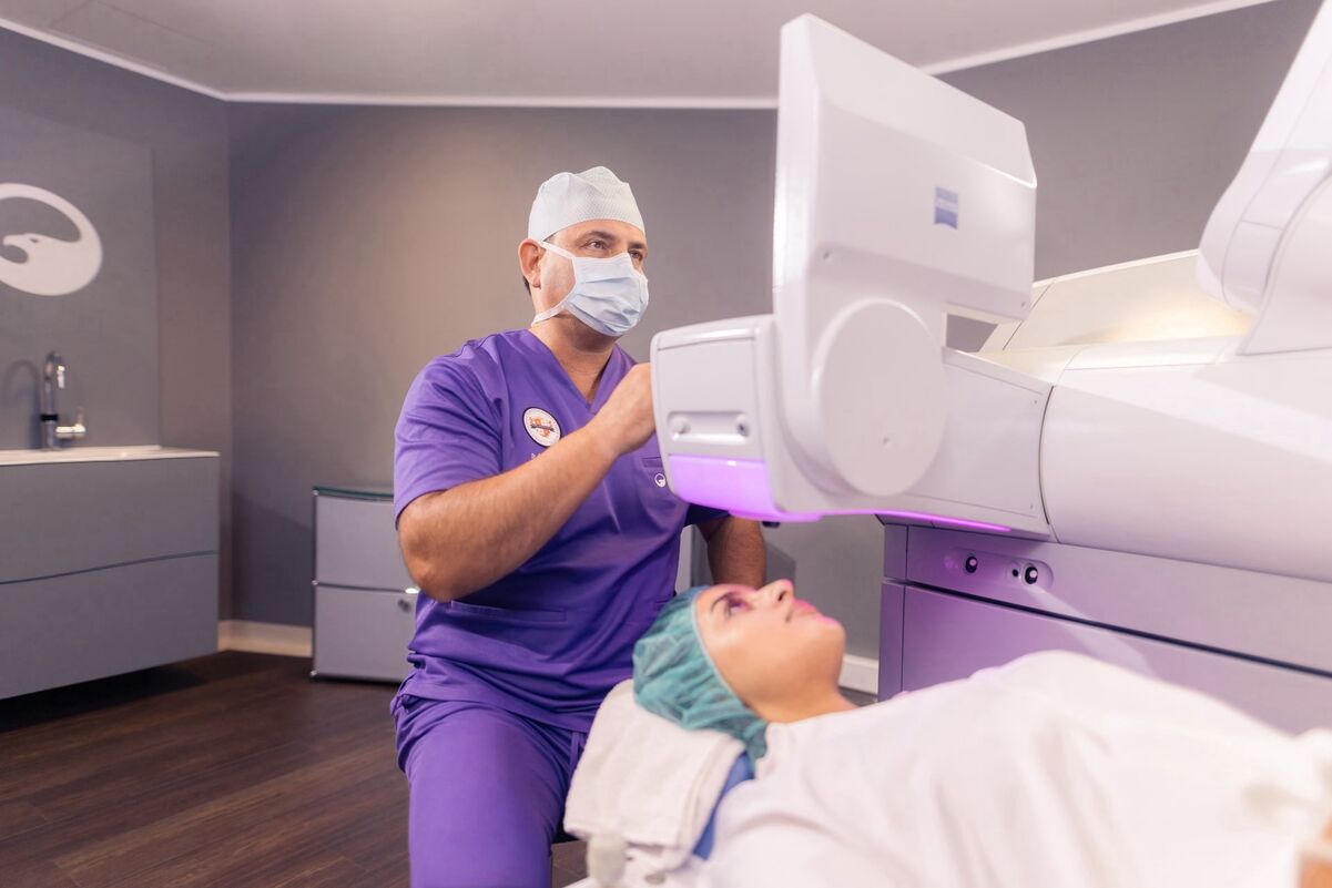 Dr. Breyer am Monitor des VISUMAX und bereitet die Laserbehandlung vor. Im Vordergrund ist eine Patientin zu sehen.