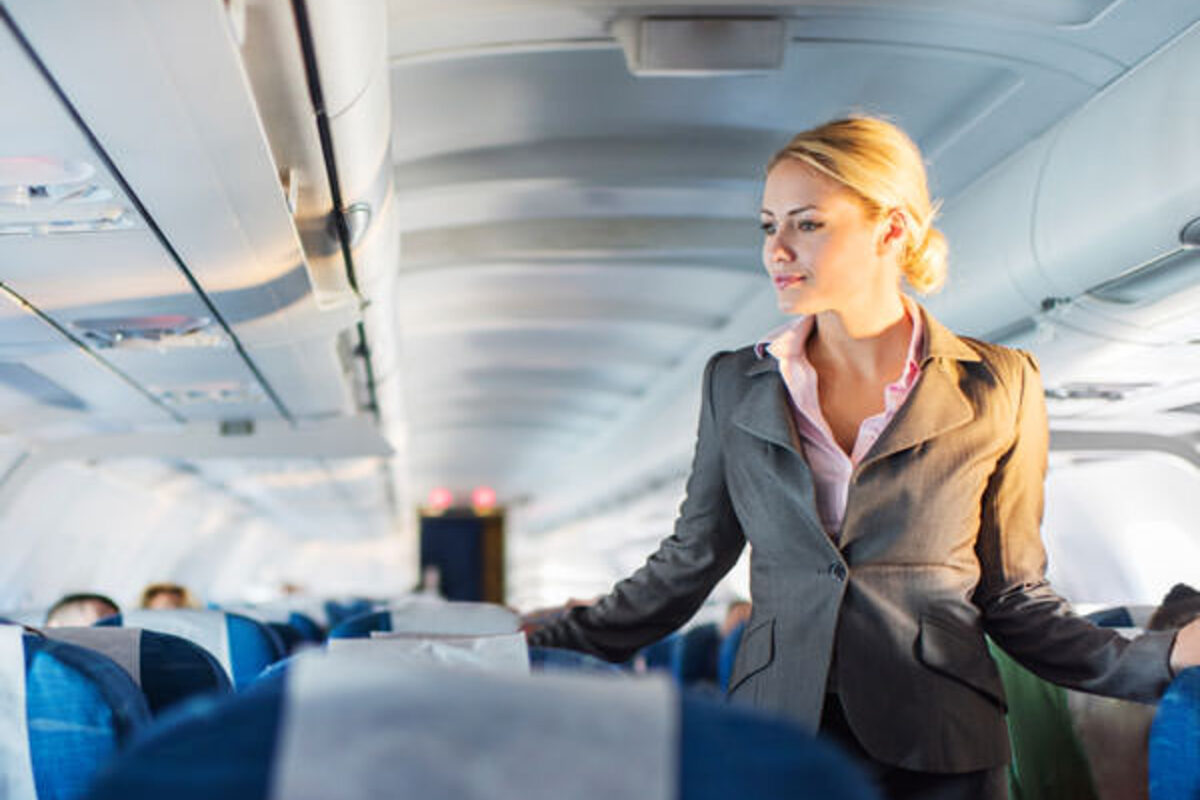 Stewardess geht zwischen Sitzreihen im Flugzeug