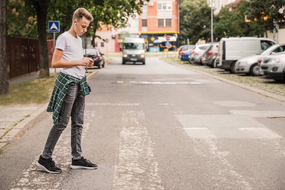Obwohl er sich auf sein Smartphone konzentriert, wird dieser junge Mann das sich nähernde Fahrzeug in der Peripherie wahrnehmen. © Dobrila Vignjevic