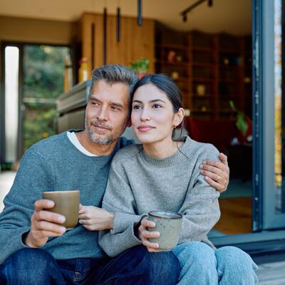 Paar mittleren Alters sitzt auf der Veranda und blickt in die Ferne.