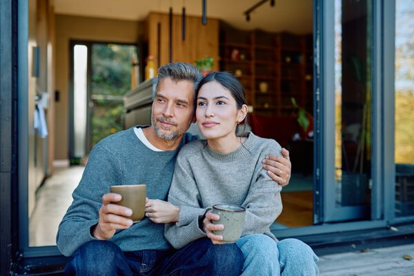 Paar mittleren Alters sitzt auf der Veranda und blickt in die Ferne.