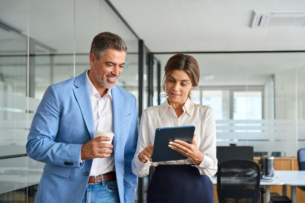 Manager und seine Kollegin schauen sich Unternehmenszahlen auf dem Tablet an.