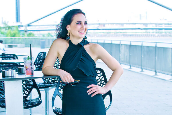 Unsere Patientin nach ihrer Linsen-OP im schwarzen Kleid auf einer Terrasse.