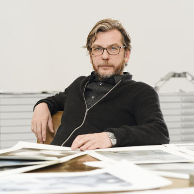 Portrait von Thomas Ruff am Tisch in seinem Atelier.